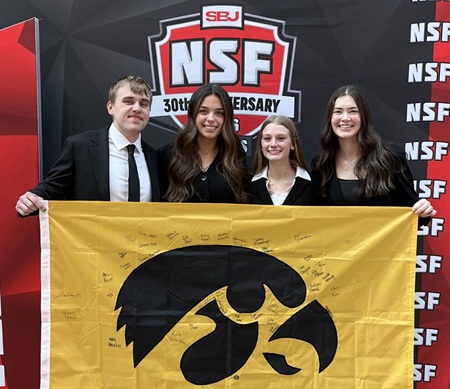 Four students holding Hawkeye flag.
