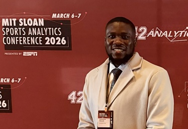 Emmanuel standing in front of wallpaper