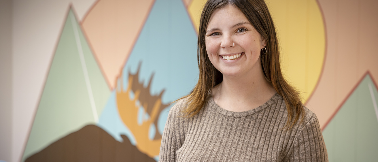HHP graduate student portrait stnading in front of painted play lab wall