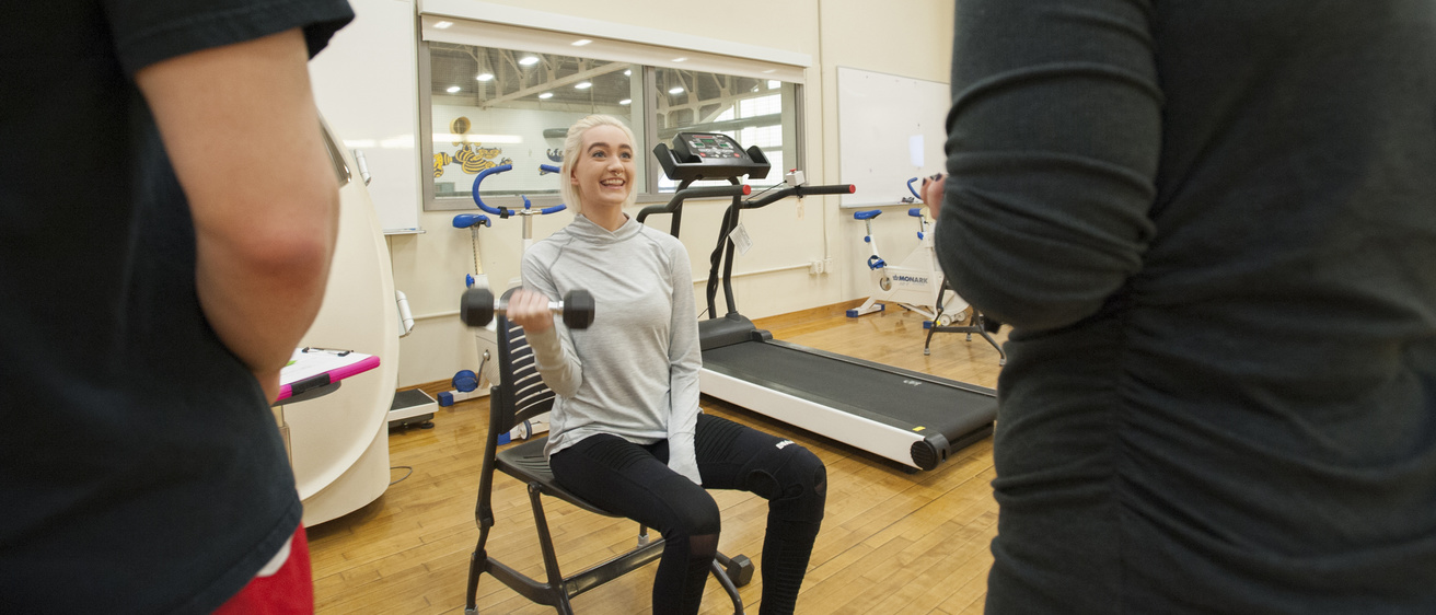 student lifting weights while being evaluated