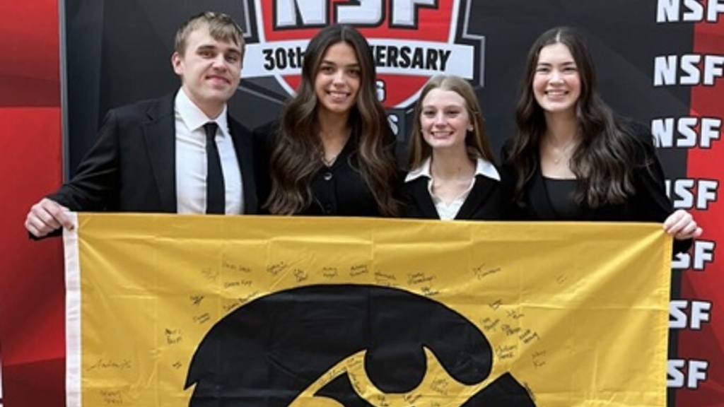 Four students holding Hawkeye flag.
